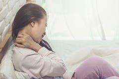 Азиатская боль в спине женщины и сидит на кровати стоковые изображения rf Азиатская боль в спине женщины и сидит на кровати стоковые изображения rf