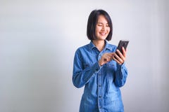 Азиатская девушка с голубым телефоном удерживания руки левой стороны рубашки стоковое изображение Азиатская девушка с голубым телефоном удерживания руки левой стороны рубашки стоковое изображение