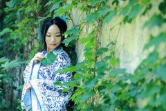 Азиатская китайская женщина в традиционном голубом и белом платье Hanfu, игре в известном саде около стены стоковое фото Азиатская китайская женщина в традиционном голубом и белом платье Hanfu, игре в известном саде около стены стоковое фото