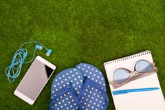 аксессуары моды - темповые сальто сальто, умный телефон с наушниками, блокнот, солнечные очки на траве стоковое изображение rf аксессуары моды - темповые сальто сальто, умный телефон с наушниками, блокнот, солнечные очки на траве стоковое изображение rf