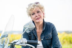 Активная старшая женщина нося голубую куртку джинсовой ткани пока сидящ дальше стоковое фото rf Активная старшая женщина нося голубую куртку джинсовой ткани пока сидящ дальше стоковое фото rf