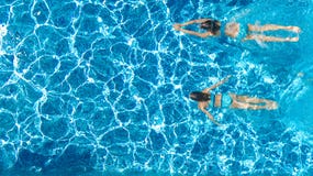 Активные девушки во взгляде трутня воды бассейна воздушном сверху, дети плавают, дети имеют потеху на тропическом семейном отдыхе стоковое фото rf Активные девушки во взгляде трутня воды бассейна воздушном сверху, дети плавают, дети имеют потеху на тропическом семейном отдыхе стоковое фото rf