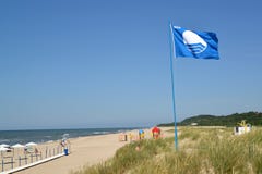 АМБЕР, РОССИЯ Международный знак флага пляжей голубого порхает над пляжем города, областью Калининграда стоковые изображения АМБЕР, РОССИЯ Международный знак флага пляжей голубого порхает над пляжем города, областью Калининграда стоковые изображения