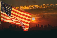 Американский флаг развевая ввиду захода солнца Манхаттана Нью-Йорка на предпосылке Стоковые Фото Американский флаг развевая ввиду захода солнца Манхаттана Нью-Йорка на предпосылке Стоковые Фото