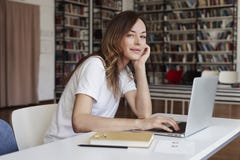 Аналитик волос молодой женщины длинный работая на со-работая офисе на компьтер-книжке, взгляде к камере, спокойной стороне, книжн стоковое изображение Аналитик волос молодой женщины длинный работая на со-работая офисе на компьтер-книжке, взгляде к камере, спокойной стороне, книжн стоковое изображение