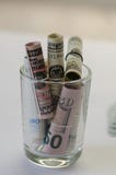 Банкноты доллара и евро в стеклянной бутылке на таблице стоковые изображения rf Банкноты доллара и евро в стеклянной бутылке на таблице стоковые изображения rf