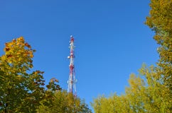 Башня ТВ радио связи мобильного телефона, рангоут, антенны микроволны клетки и передатчик против голубого неба и деревьев Стоковое Изображение Башня ТВ радио связи мобильного телефона, рангоут, антенны микроволны клетки и передатчик против голубого неба и деревьев Стоковое Изображение