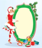Белокурая девушка xmas нося костюм Санта Клауса оставаясь рядом с рамкой Стоковая Фотография Белокурая девушка xmas нося костюм Санта Клауса оставаясь рядом с рамкой Стоковая Фотография