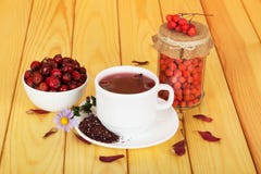 Бедра, зола горы и чай чашки на предпосылке освещают древесину Стоковая Фотография Бедра, зола горы и чай чашки на предпосылке освещают древесину Стоковая Фотография