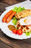Бельгийский waffle с яичком и сосиской на деревянной таблице Стоковое Изображение RF Бельгийский waffle с яичком и сосиской на деревянной таблице Стоковое Изображение RF