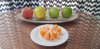 Белая плита с, который слезли кусками мандарина и блюдо с 4 яблоками различных цветов и ножа стоковая фотография rf Белая плита с, который слезли кусками мандарина и блюдо с 4 яблоками различных цветов и ножа стоковая фотография rf
