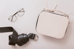 Белая сумка, черный кожаный пояс и стекла моды на бежевой предпосылке стоковое изображение Белая сумка, черный кожаный пояс и стекла моды на бежевой предпосылке стоковое изображение