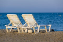 Белизна, пластичные sunbeds на золотом часе на песчаном пляже Закинфа, Греции стоковая фотография Белизна, пластичные sunbeds на золотом часе на песчаном пляже Закинфа, Греции стоковая фотография