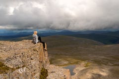 Белокурая девушка сидит опасно самостоятельно на краю скалы стоковая фотография rf Белокурая девушка сидит опасно самостоятельно на краю скалы стоковая фотография rf