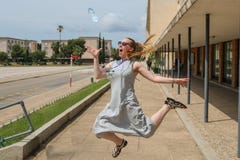 Белокурый скакать девушки, улавливая бутылку с водой стоковая фотография Белокурый скакать девушки, улавливая бутылку с водой стоковая фотография