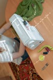 белошвейка сидя на деревянном столе со швейной машиной, работая около окна в студии стоковое фото белошвейка сидя на деревянном столе со швейной машиной, работая около окна в студии стоковое фото