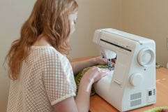Белошвейка сидя на таблице со швейной машиной стоковое изображение rf Белошвейка сидя на таблице со швейной машиной стоковое изображение rf