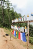 Белые пластичные колеса молитве обочины на пути к монастырю Taktshang Palphug (гнезду) тигра, Бутану стоковая фотография rf Белые пластичные колеса молитве обочины на пути к монастырю Taktshang Palphug (гнезду) тигра, Бутану стоковая фотография rf