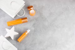 Белые хозяйственные сумки и оранжевые косметические образцы на серой конкретной предпосылке стоковая фотография Белые хозяйственные сумки и оранжевые косметические образцы на серой конкретной предпосылке стоковая фотография