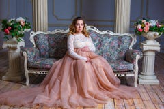 Беременная женщина сидя в красивом платье на кресле Концепция материнства стоковое фото rf Беременная женщина сидя в красивом платье на кресле Концепция материнства стоковое фото rf