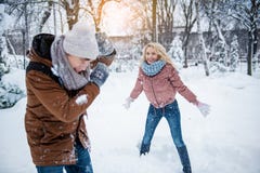Беспечальный молодой человек и женщина играя снежные комья стоковое изображение rf Беспечальный молодой человек и женщина играя снежные комья стоковое изображение rf
