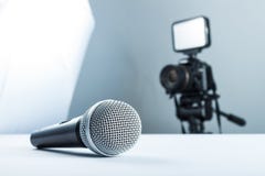 Беспроводной микрофон лежа на белой таблице на фоне камеры DSLR к свету приведенному стоковое фото rf Беспроводной микрофон лежа на белой таблице на фоне камеры DSLR к свету приведенному стоковое фото rf