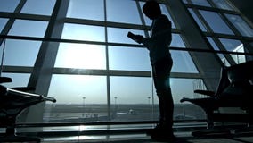 Бизнесмен используя планшет на авиапорте силуэт путешественника человека с рюкзаком Дело и перемещение видеоматериал Бизнесмен используя планшет на авиапорте силуэт путешественника человека с рюкзаком Дело и перемещение видеоматериал