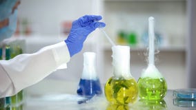 Биохимик беря желтый органический образец вещества от склянки, извлечения завода стоковое изображение Биохимик беря желтый органический образец вещества от склянки, извлечения завода стоковое изображение
