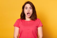 Близкий поднимающий вверх портрет молодой женщины брюнета смотря удивленный, стоящ с широким открытым ртом, нося красная футболка стоковое изображение rf Близкий поднимающий вверх портрет молодой женщины брюнета смотря удивленный, стоящ с широким открытым ртом, нося красная футболка стоковое изображение rf