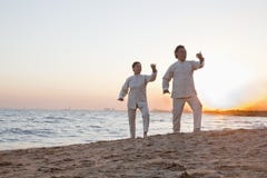 2 более старых люд практикуя Taijiquan на пляже на заходе солнца, Китае Стоковые Фотографии RF 2 более старых люд практикуя Taijiquan на пляже на заходе солнца, Китае Стоковые Фотографии RF