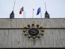 Большие часы на городской ратуше, развевающ румынские и европейские ф стоковые изображения rf Большие часы на городской ратуше, развевающ румынские и европейские ф стоковые изображения rf