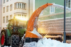 Большой трактор с цепями на низовой метели колеса с улицы города в тело самосвала Очищая улицы и удаление снега позже стоковое изображение rf Большой трактор с цепями на низовой метели колеса с улицы города в тело самосвала Очищая улицы и удаление снега позже стоковое изображение rf
