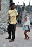 Босоногие африканские дети идут вдоль рыбацкого поселка, Zanzib Стоковое Изображение RF Босоногие африканские дети идут вдоль рыбацкого поселка, Zanzib Стоковое Изображение RF