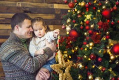Будьте отцом и его маленькая дочь украшая рождественскую елку на стоковые изображения rf Будьте отцом и его маленькая дочь украшая рождественскую елку на стоковые изображения rf
