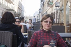 Будапешт, Венгрия - 9-ое апреля 2018: средн-достигшая возраста женщина сидя на террасе кафа самостоятельно и смотря камеру, внешн стоковая фотография Будапешт, Венгрия - 9-ое апреля 2018: средн-достигшая возраста женщина сидя на террасе кафа самостоятельно и смотря камеру, внешн стоковая фотография