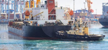 Буксир на смычке грузового корабля, помогая сосуду для того чтобы провести маневр стоковое изображение Буксир на смычке грузового корабля, помогая сосуду для того чтобы провести маневр стоковое изображение