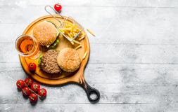 Бургеры с пивом, томатами и французским картофелем фри на разделочной доске стоковое фото rf Бургеры с пивом, томатами и французским картофелем фри на разделочной доске стоковое фото rf