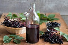 Бутылка домодельного сиропа elderberry на деревянном столе стоковое изображение rf Бутылка домодельного сиропа elderberry на деревянном столе стоковое изображение rf