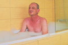 ванна имея человека Человек постаретый серединой расслабляющий в ванне вполне пены Зрелый человек в ванной комнате стоковая фотография rf ванна имея человека Человек постаретый серединой расслабляющий в ванне вполне пены Зрелый человек в ванной комнате стоковая фотография rf