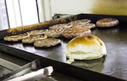 Варящ и изнашивающ бургеры и гамбургеры на гриле с хлебцем хлеба стоковые изображения rf Варящ и изнашивающ бургеры и гамбургеры на гриле с хлебцем хлеба стоковые изображения rf