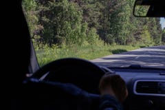 Взгляд дороги леса от ветрового стекла автомобиля Рука водителя держа руль, в defocus стоковые фото Взгляд дороги леса от ветрового стекла автомобиля Рука водителя держа руль, в defocus стоковые фото