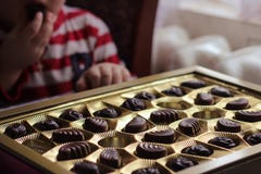 Взгляд крупного плана коробки шоколадов еда ребенка конфеты жадность стоковое фото rf Взгляд крупного плана коробки шоколадов еда ребенка конфеты жадность стоковое фото rf