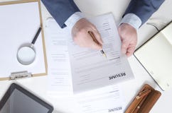 Взгляд сверху таблицы специалиста по набору персонала который работая с резюмем и выбирая большего работника стоковое изображение Взгляд сверху таблицы специалиста по набору персонала который работая с резюмем и выбирая большего работника стоковое изображение