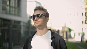 Взгляд со стороны молодого человека в солнечных очках принимая смартфон из его кармана видеоматериал Взгляд со стороны молодого человека в солнечных очках принимая смартфон из его кармана видеоматериал