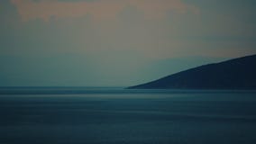 Взморье с темными холмами на заходе солнца Взморье с темными холмами на заходе солнца