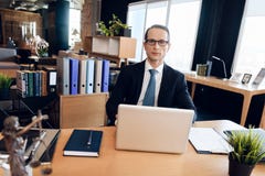 Взрослый уверенно человек в костюме сидит на таблице в офисе Юрист на работе стоковое фото Взрослый уверенно человек в костюме сидит на таблице в офисе Юрист на работе стоковое фото