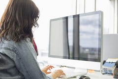 Вид сзади коммерсантки используя настольный компьютер в творческом офисе стоковая фотография rf Вид сзади коммерсантки используя настольный компьютер в творческом офисе стоковая фотография rf
