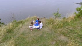 Вид с воздуха на 3 девушках нося длинное платье моды лета сидя около озера или реки 2 кавказское и одно акции видеоматериалы Вид с воздуха на 3 девушках нося длинное платье моды лета сидя около озера или реки 2 кавказское и одно акции видеоматериалы