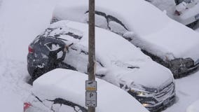 Вид с воздуха снега и льда чистки женщины с ее окна ветровой защиты автомобиля Вид с воздуха снега и льда чистки женщины с ее окна ветровой защиты автомобиля