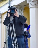 Видео- оператор за деятельностью и журналистом идет интервьюировать стоковое изображение rf Видео- оператор за деятельностью и журналистом идет интервьюировать стоковое изображение rf